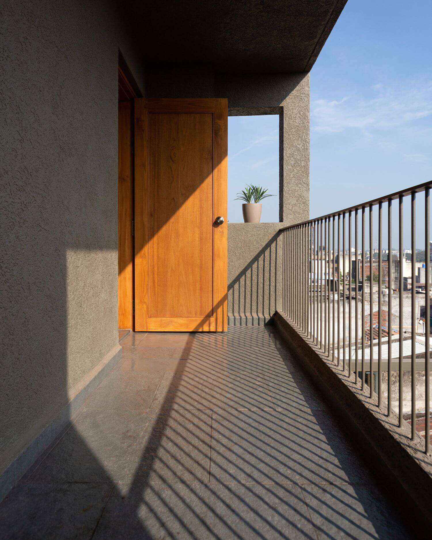 The balcony with timber door and shadows cast by a slender metal railing