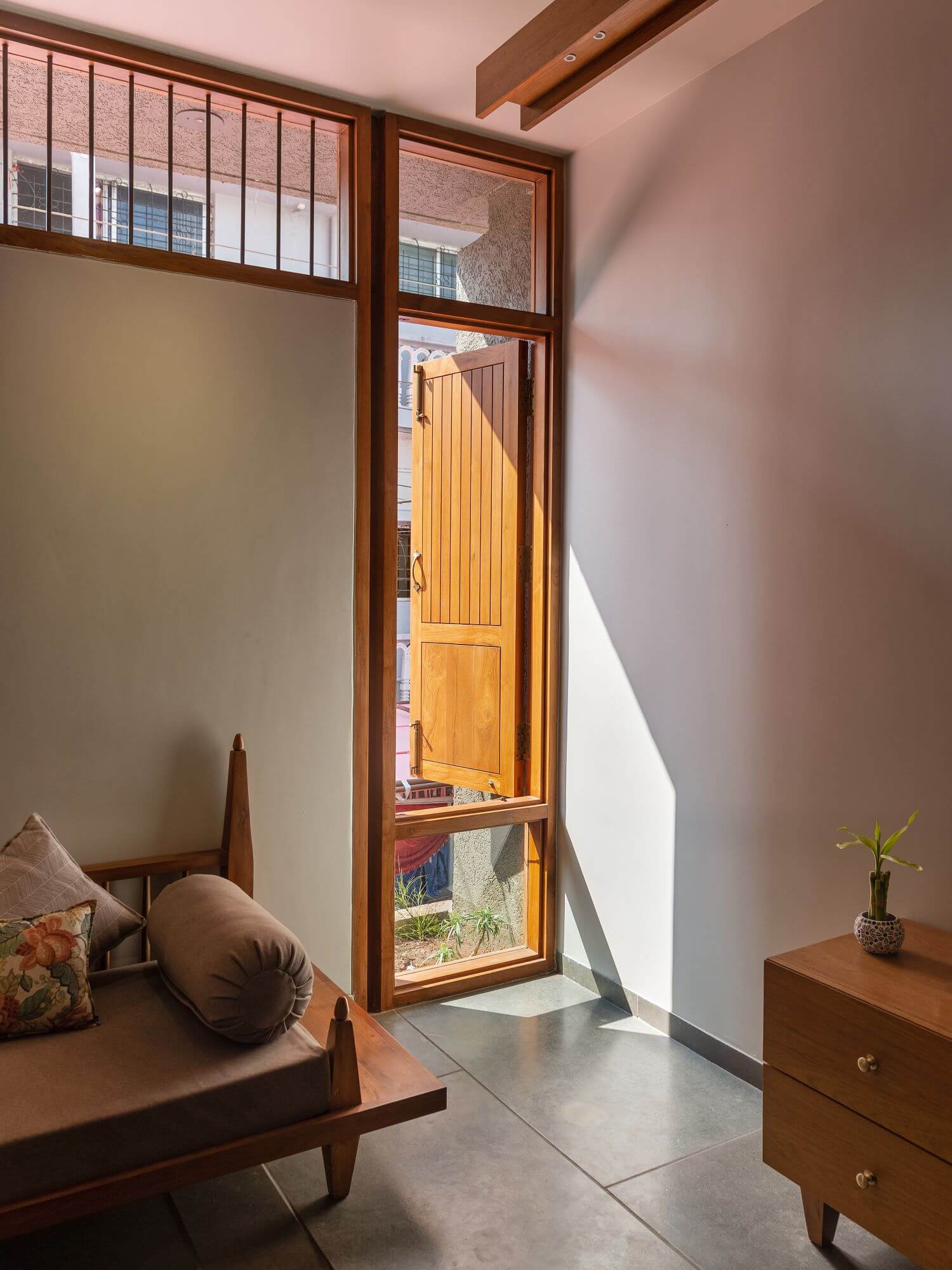 Sunlight entering through a tall timber window beside the living room