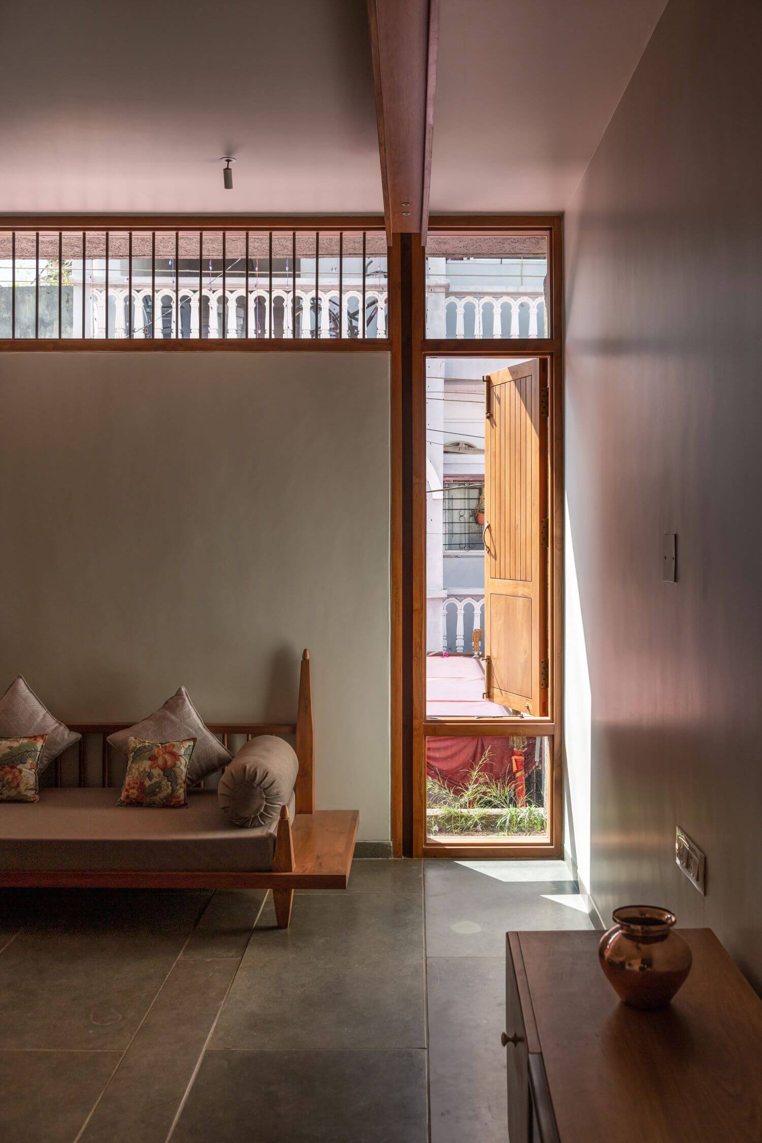 The timber window, sofa and console with a ceramic vessel